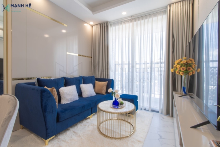 Thi công nội thất phòng khách với bộ ghế sofa vải màu xanh bằng vải nhung làm điểm nhấn nổi bật cho căn phòng
