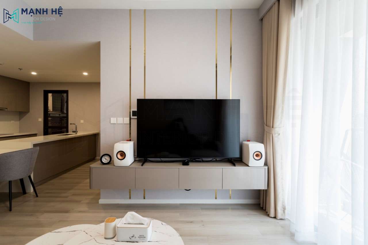 Hệ tủ tivi treo tường dường như trở nên nổi bật hơn nhờ những đường chỉ nẹp vàng chạy dọc tường