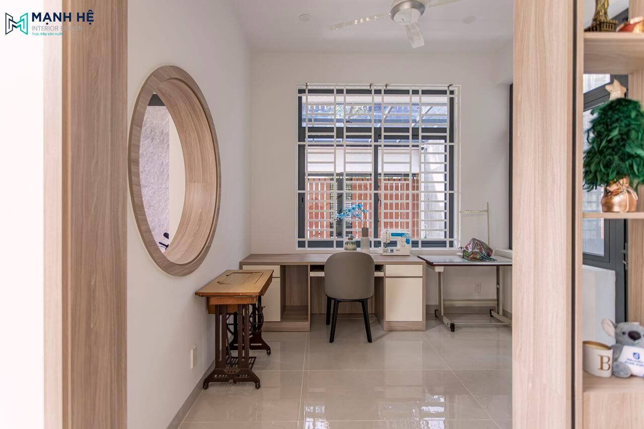 Thi công 1 phòng may đồ nhỏ cho gia chủ ngay cạnh phòng khách, với 1 chiếc bàn gỗ công nghiệp tiện nghi với nhiều học tủ