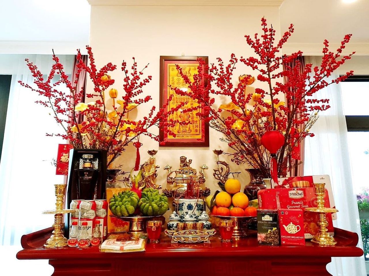 Trang hoàng bàn thờ gia tiên tươm tất với hoa đào đỏ và lễ vật để tỏ lòng thành kính với ông bà tổ tiên.