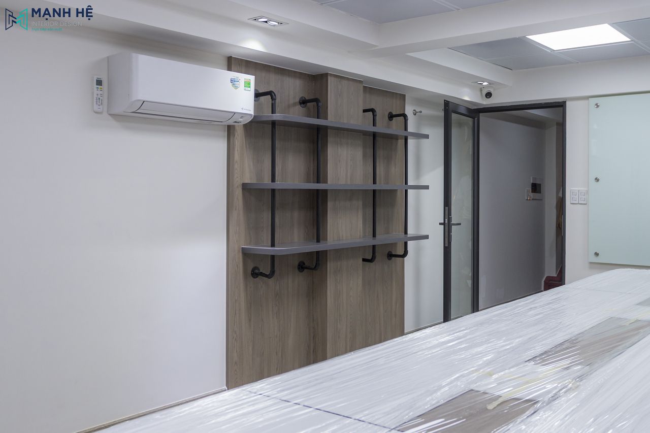 Phòng họp sử dụng chất liệu gỗ công nghiệp với vân gỗ tự nhiên và có bố trí kệ sách treo tường cùng màu