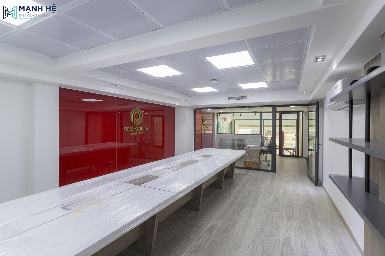 Không gian phòng họp rộng rãi với cửa kính lớn và bố trí dãy bàn họp dài hình chữ nhật, làm từ chất liệu gỗ công nghiệp màu sáng