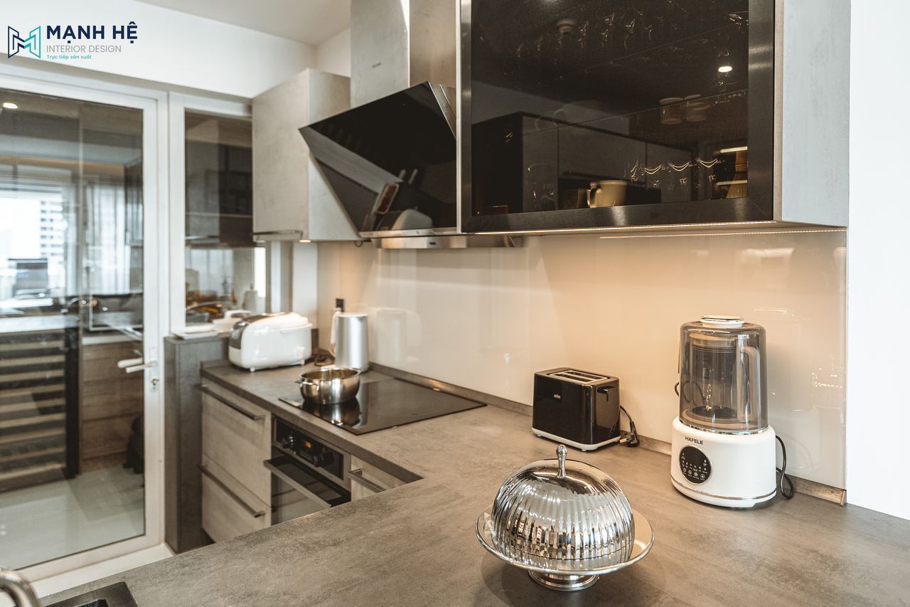 Tủ bếp chữ L kết hợp hệ tủ trên cánh kính cường lực tăng không gian lưu trữ và tích hợp máy hút mùi