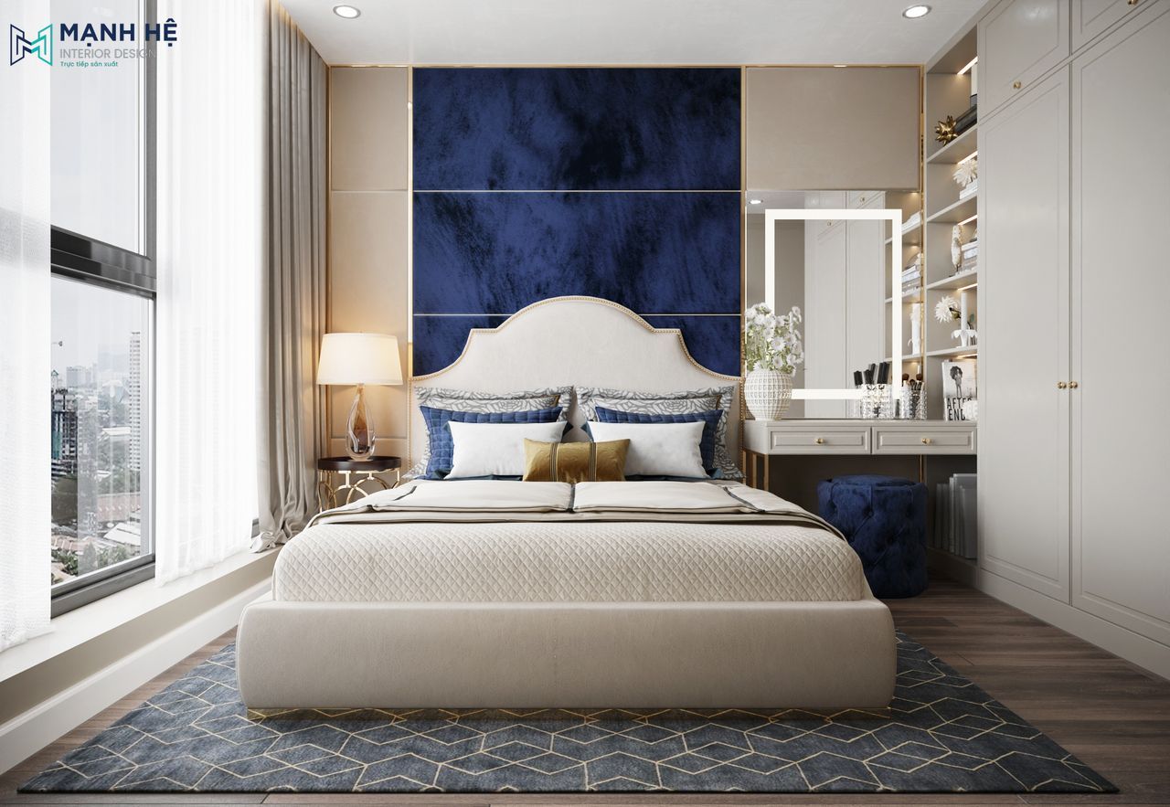 Phòng ngủ nhỏ phong cách tân cổ điển với vách đầu giường nhung xanh navy, giường bọc nệm sáng màu, bàn trang điểm liền hệ tủ và ánh sáng tự nhiên tràn ngập.