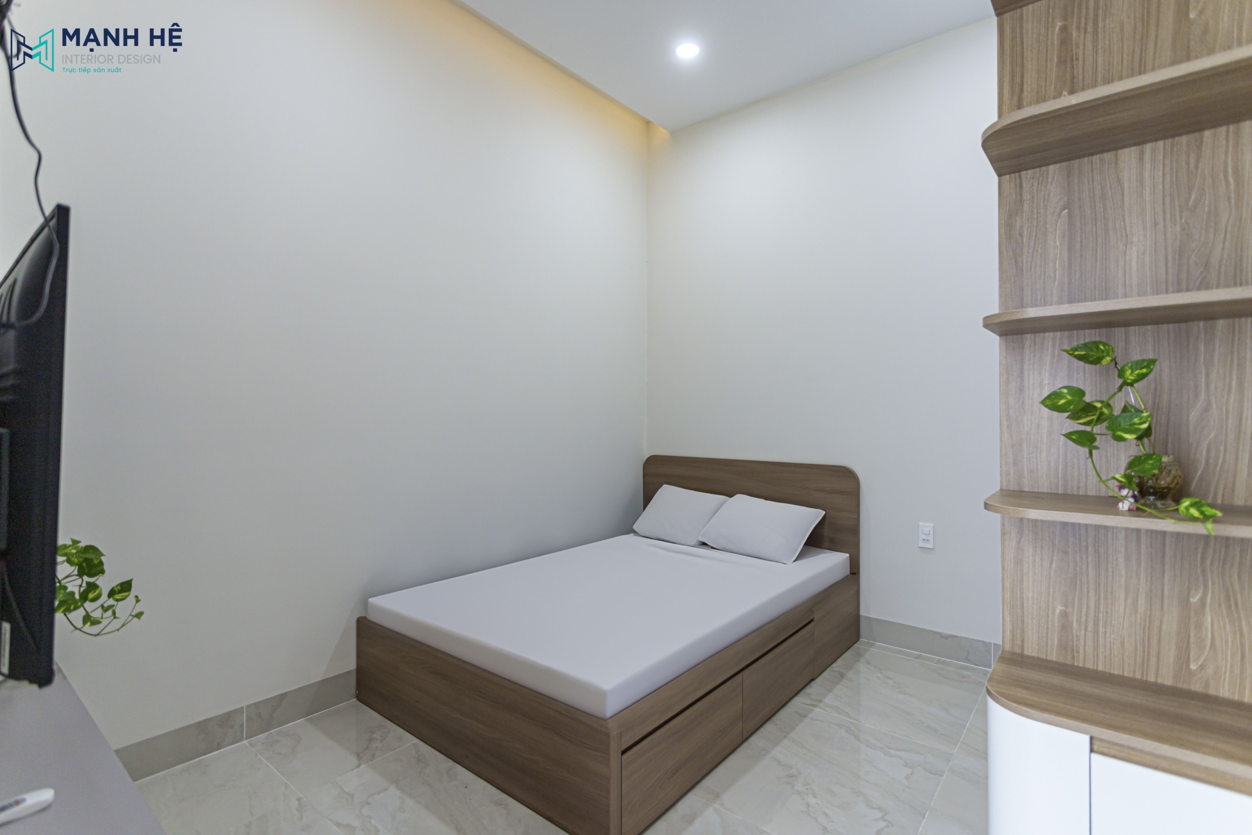 Giường ngủ gỗ tích hợp hộc kéo, đặt sát góc tường trong phòng ngủ nhỏ cùng ánh sáng đèn trần hắt ấm cúng