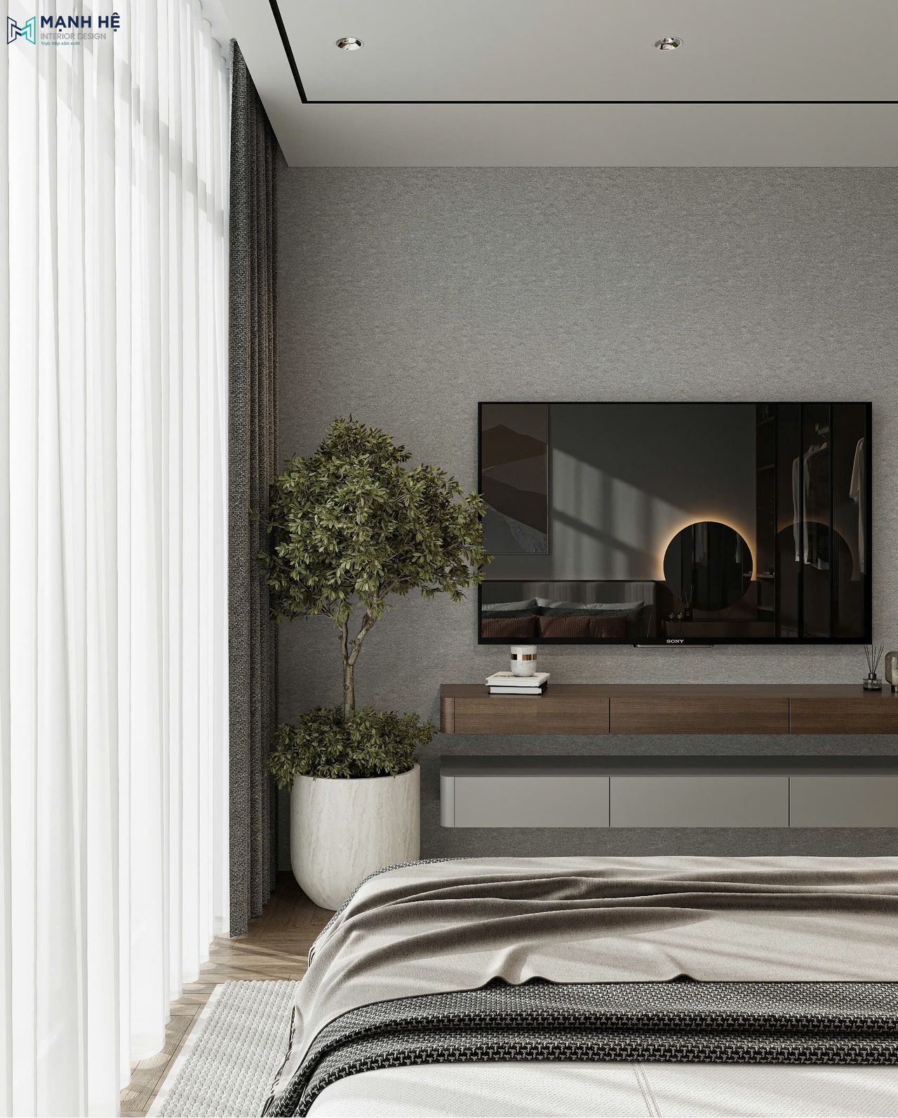 Hệ kệ tivi treo tường gồm tủ trên màu nâu vân gỗ và tủ dưới màu xám,bên cạnh là chậu cây xanh giúp làm mềm không gian phòng ngủ