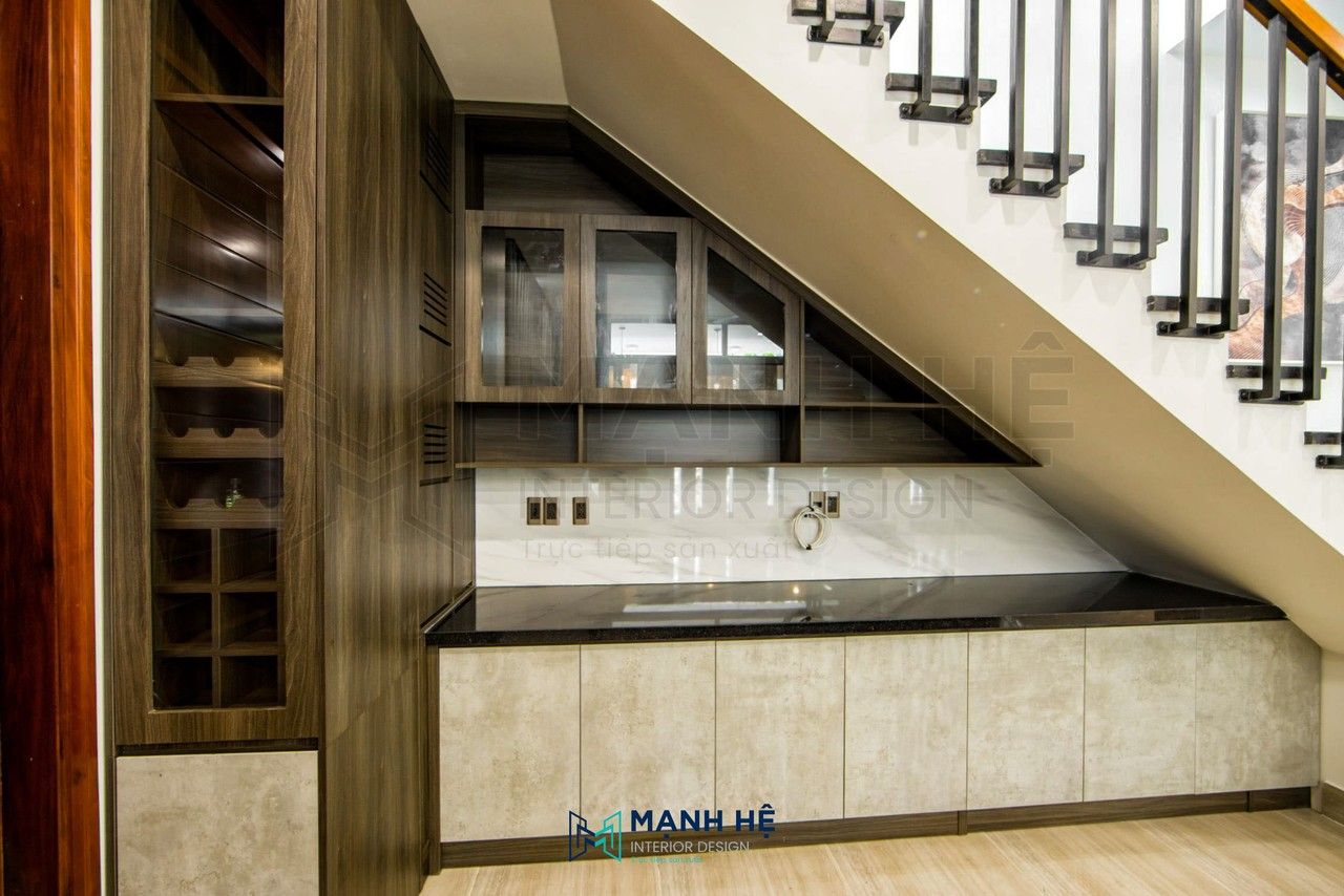 Hệ tủ chạy dọc theo dốc gầm cầu thang, khoang kính đặt ở đoạn cao để trưng bày, khoang kín gom về đoạn thấp để lưu trữ