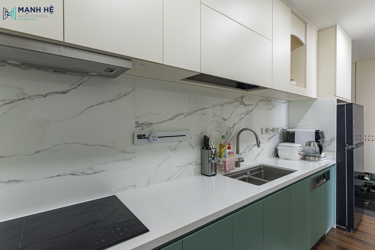 Không gian bếp trở nên thanh lịch và hài hòa hơn nhờ bề mặt đá ốp bếp vân mây, sắp xếp khoa học giữa bếp từ và chậu rửa giúp thao tác thuận tiện