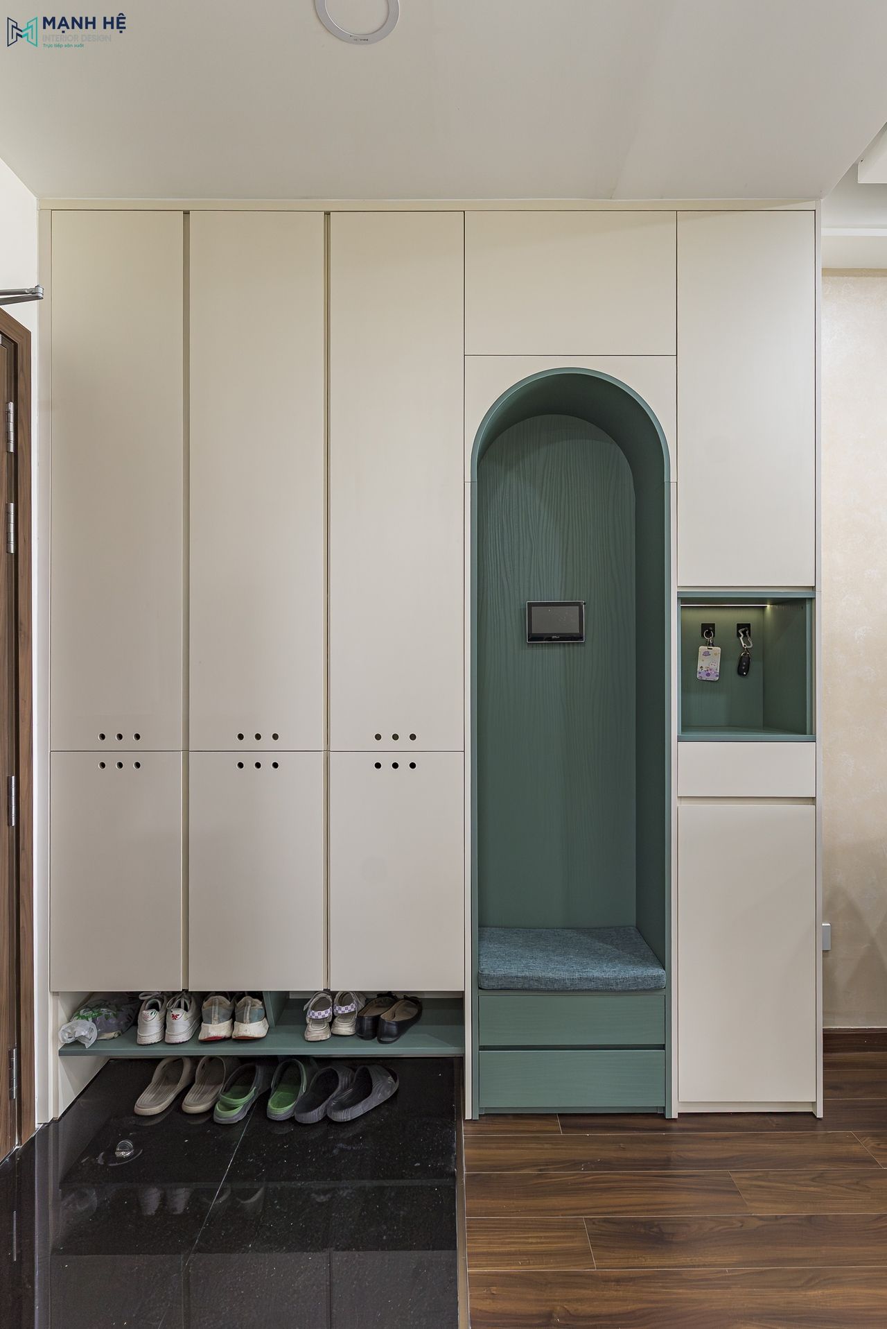 Tủ giày kịch trần màu trắng kem kết hợp ghế ngồi bọc nệm xanh và hộc mở bên dưới, tăng tiện ích lưu trữ và giữ lối vào gọn gàng