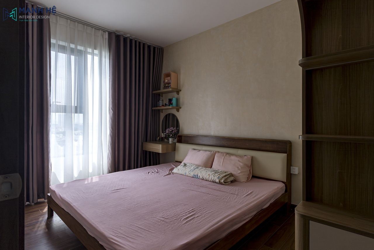 Phòng ngủ master với giường gỗ, ga màu hồng pastel và rèm hai lớp, tạo nên không gian nghỉ ngơi ấm cúng và hiện đại