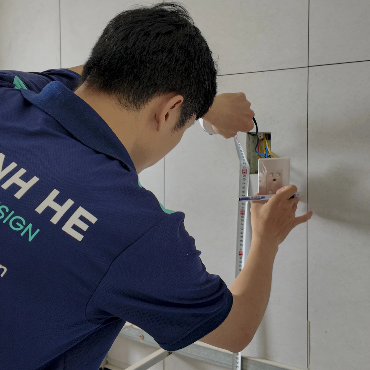 Kiến trúc sư Mạnh Hệ đo kích thước thực tế bằng thước dây đo khoảng cách từ sàn đến ổ điện trên tường để tính toán diện tích phòng