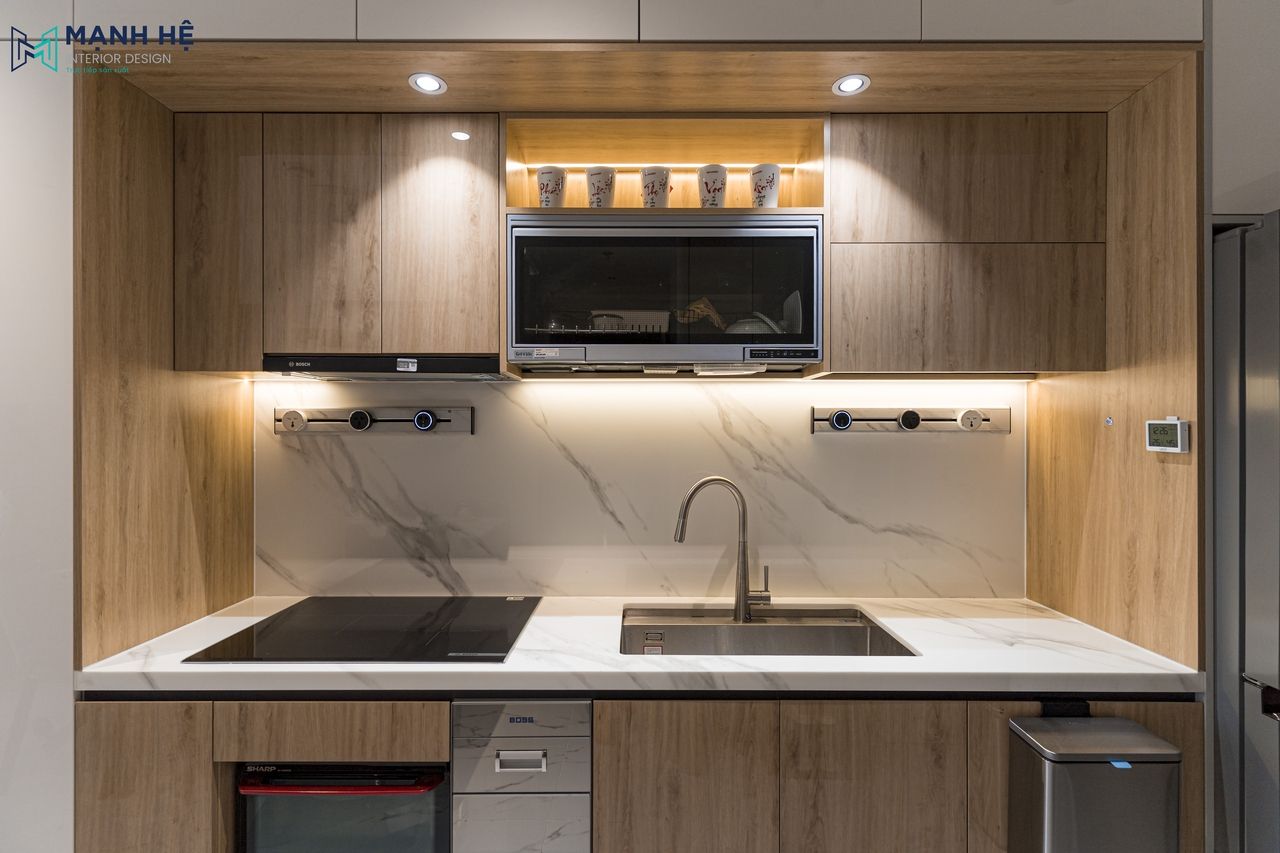 Hệ tủ trên và tủ dưới được thi công đồng bộ với chất liệu acrylic bóng gương hiện đại tích hợp các thiết bị bếp gọn gàng