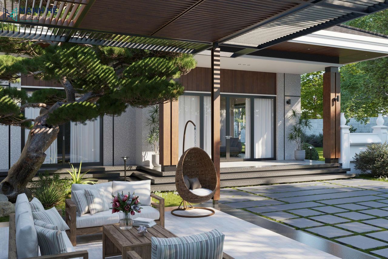 Góc sân vườn với sofa gỗ, ghế treo và cây tùng lớn tạo không gian thư giãn ngoài trời.