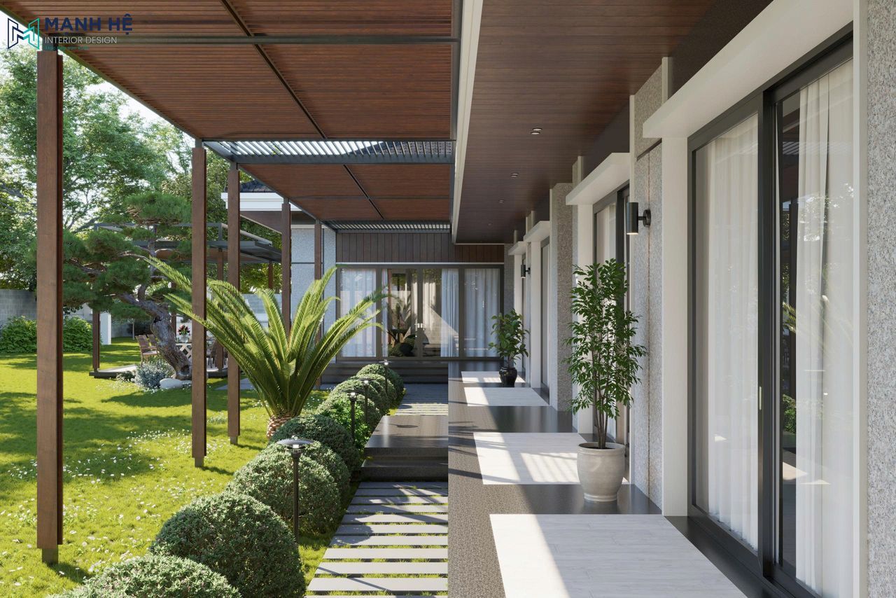 Lối hành lang ngoài trời có mái gỗ, hàng cây trang trí và cửa kính lớn nhìn ra sân vườn