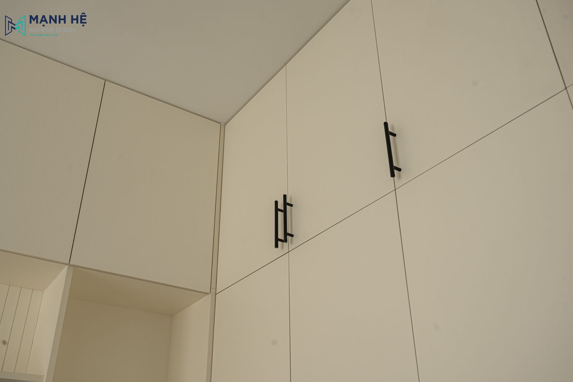 Chi tiết tay nắm tủ đen được lắp đặt chuẩn xác trên bề mặt tủ gỗ phẳng mịn, đảm bảo độ bền và tính thẩm mỹ khi sử dụng.